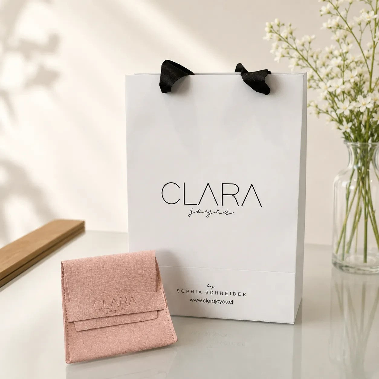 Pulsera irregular de plata de Sophia Schneider Joyas junto a una bolsa de regalo y estuche de gamuza rosa